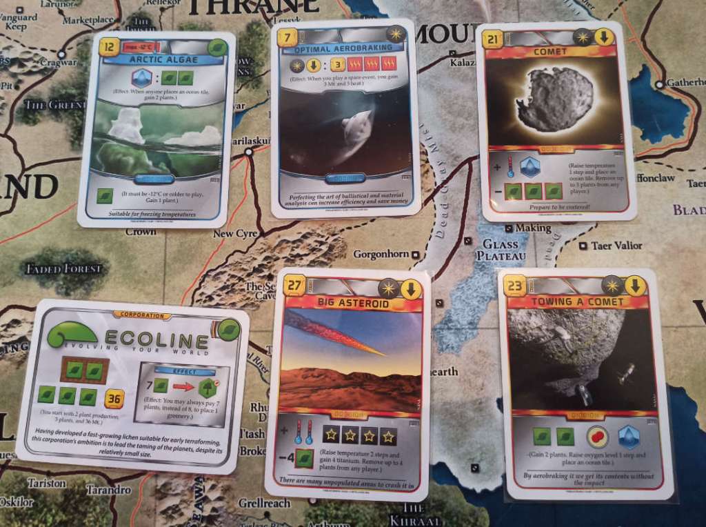 The cards, starting from the top left and moving clockwise, are:
Arctic Algae: Every time an Ocean is placed, gain 2 plants. Optimal Aerobraking: Every time you play a Space Event, gain 3 credits and 3 heat. Comet: Increase Temperature by 1 and place 1 Ocean. Towing a Comet: Gain 2 plans, increase Oxygen by 1, and place an Ocean. Big Asteroid: Gain 4 titanium and increase Temperature by 2. Ecoline: Corporation that starts with 2 Plant production, and can place Greenery tiles with 7 plants instead of 8.